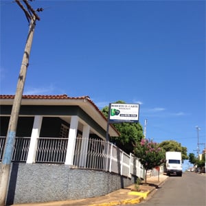 A varanda protegida pelas grades brancas contorna o escritório cinza e branco da cidade de Itamogi/MG. 